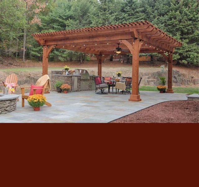 Wood Kingston Pergola on a back patio with a grill and dining set.