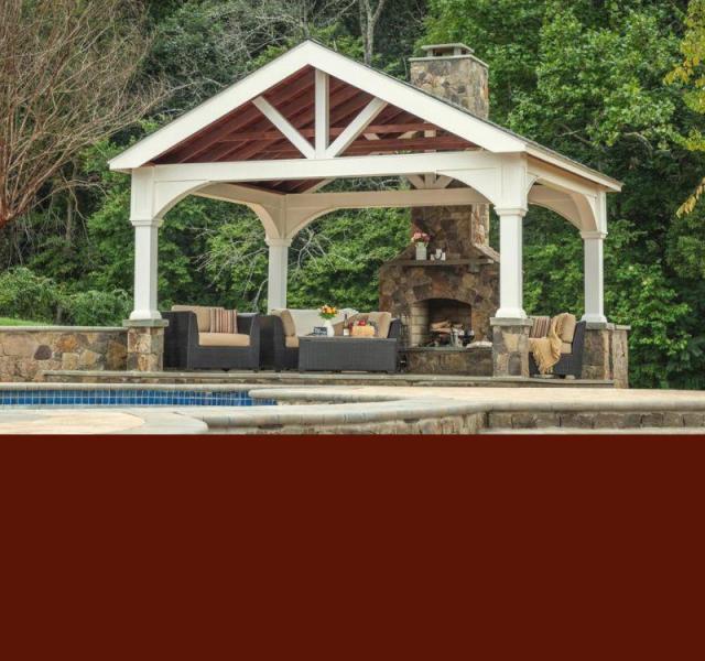 Vinyl A-Frame Pavilion in white on a back stone patio with a large stone fireplace and couches.