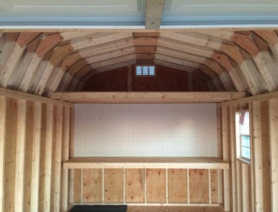 Interior of a garage with a loft, pegboard, and workbench.