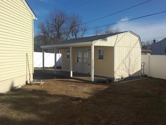 Yellow Quaker Shed with porch, beams, white double doors and windows, and grey roof